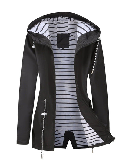 Schwarze Regenjacke liegend mit gestreiftem Futter